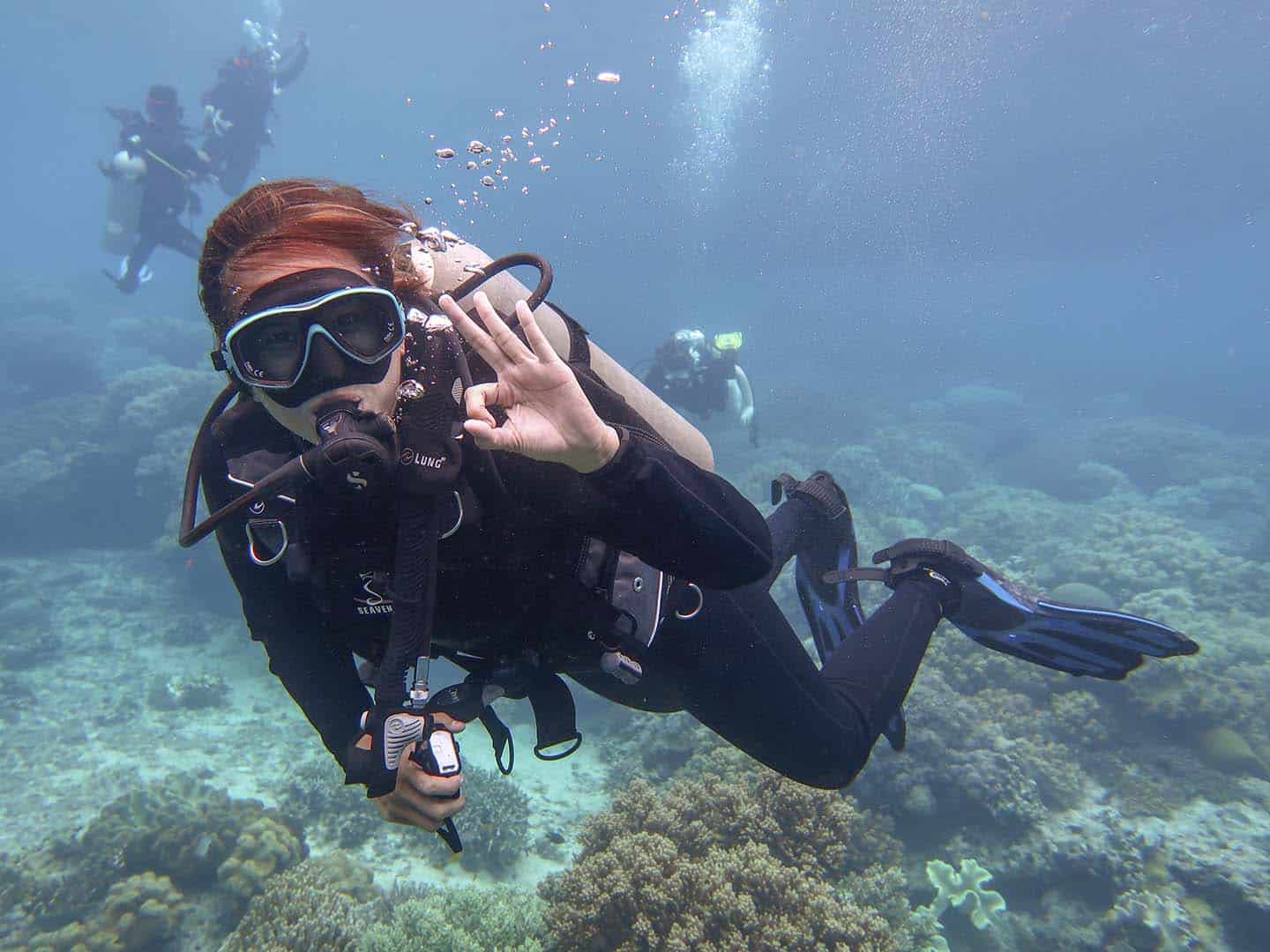 Female scuba diver with okay hand-signal while diving in Apo Island