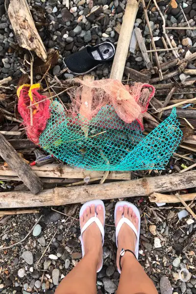 single use plastic beach trash with feet shot